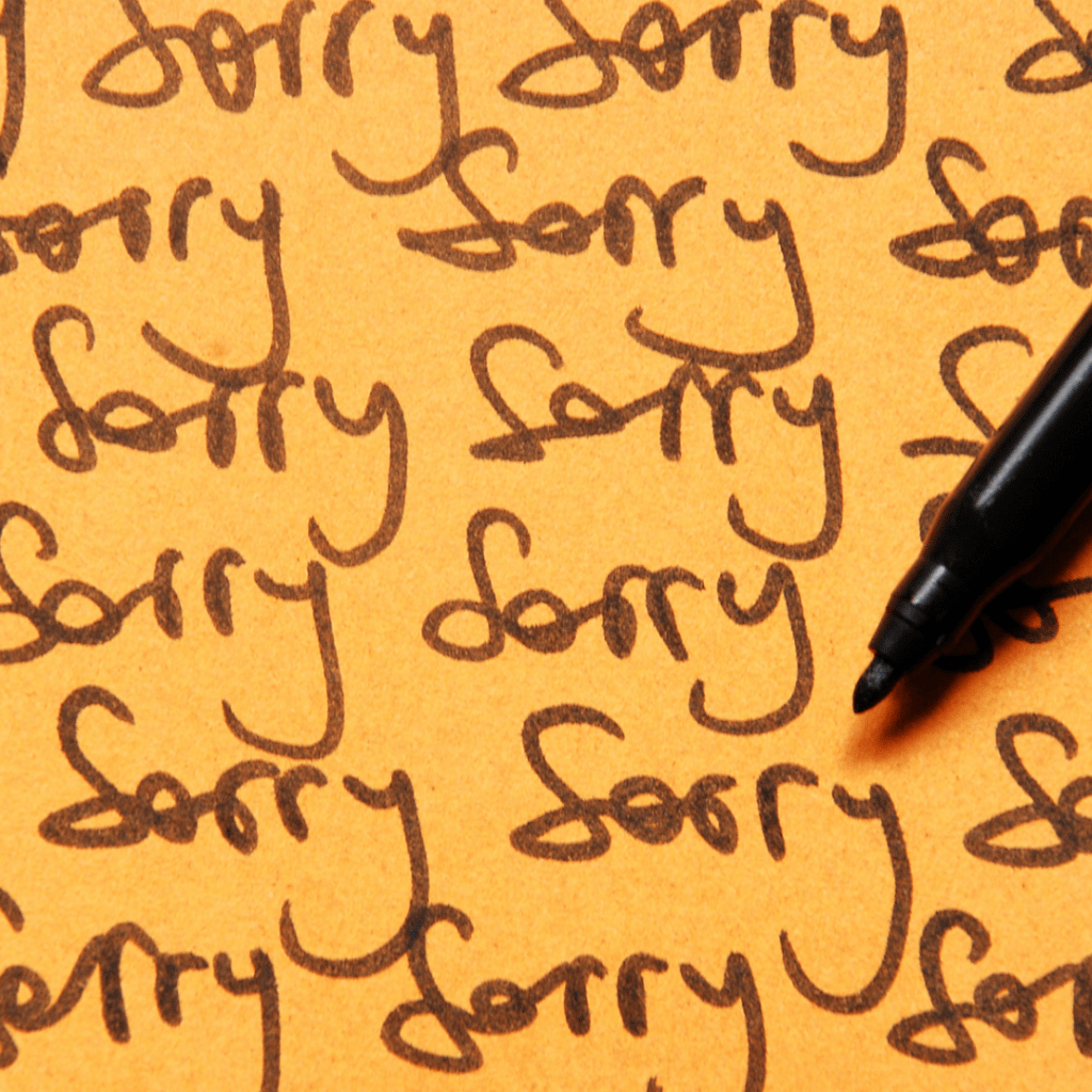 a yellow paper full of written word "sorry" using a black pen