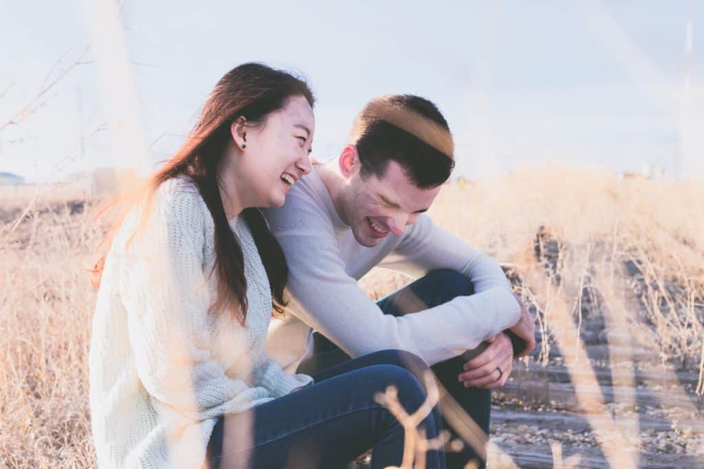 photo of an Asian woman and a white man laughing together in a daytime photo