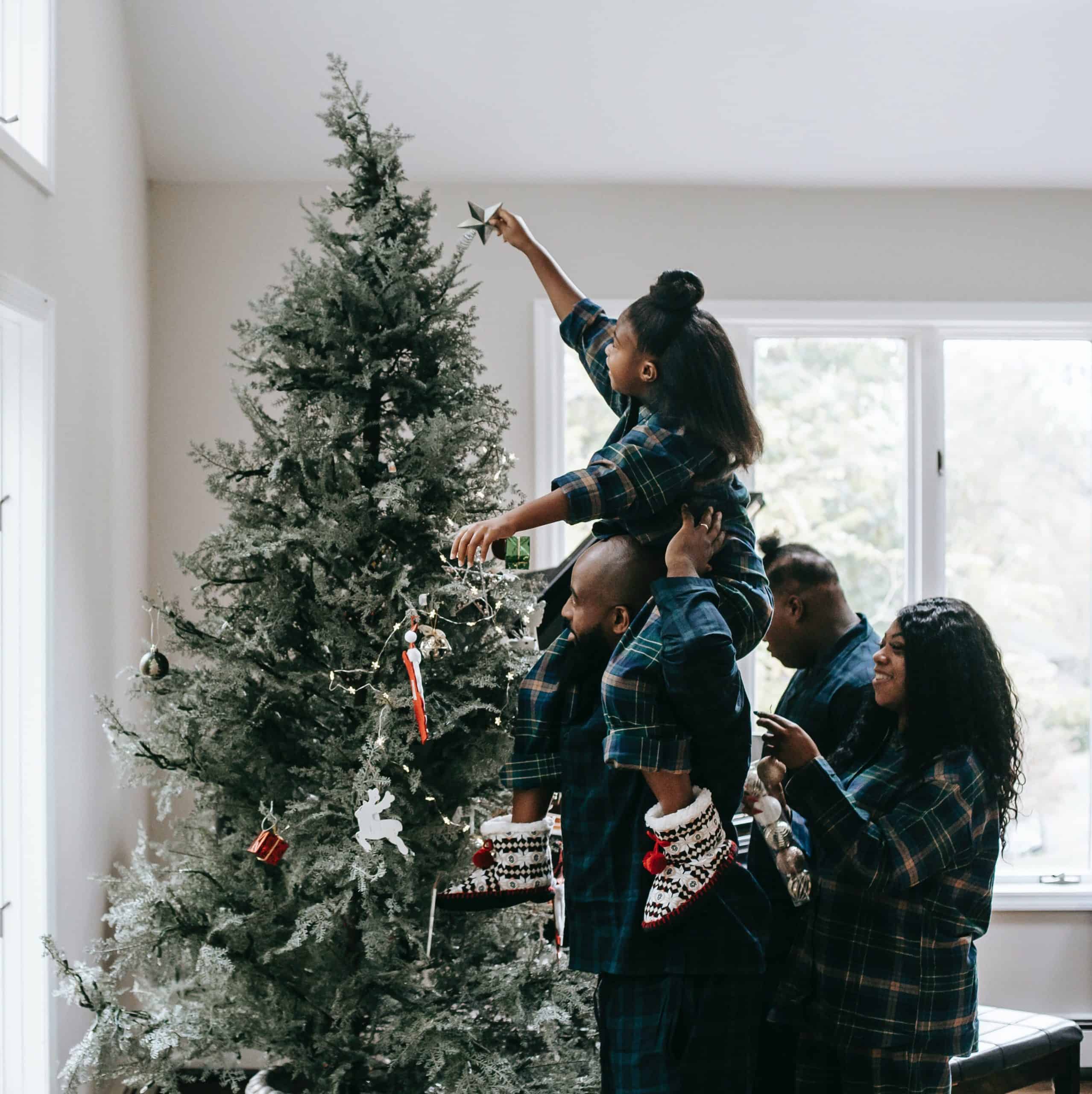 an image of a black family with mom, dad, big brother and baby sister decorating the Christmas tree