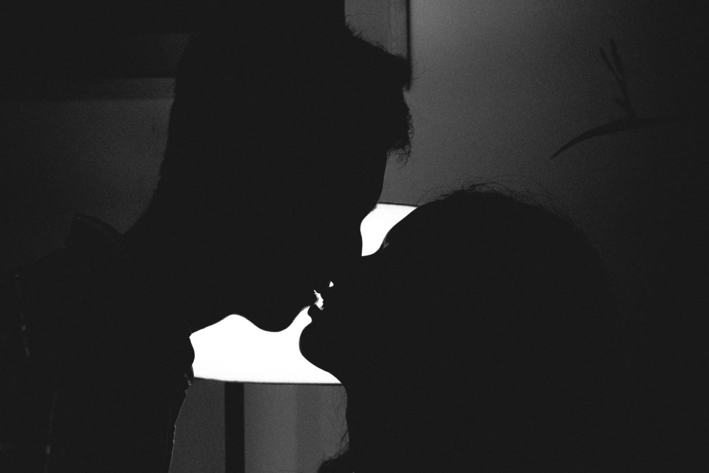 a black and white image of a couple kissing