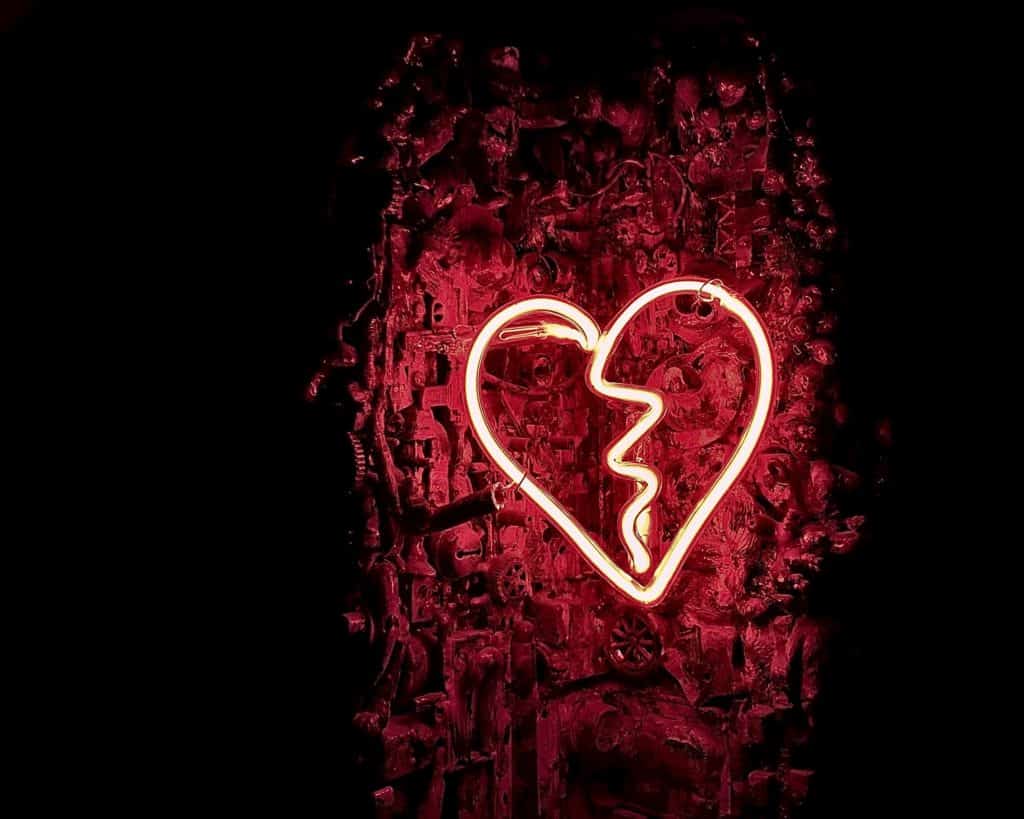 a red neon lights formed into a broken heart