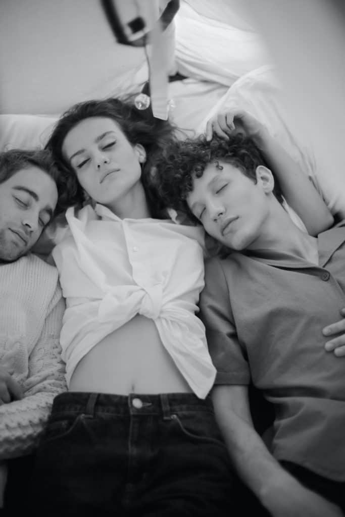 a greyscale image of a woman in the middle of two men lying in bed