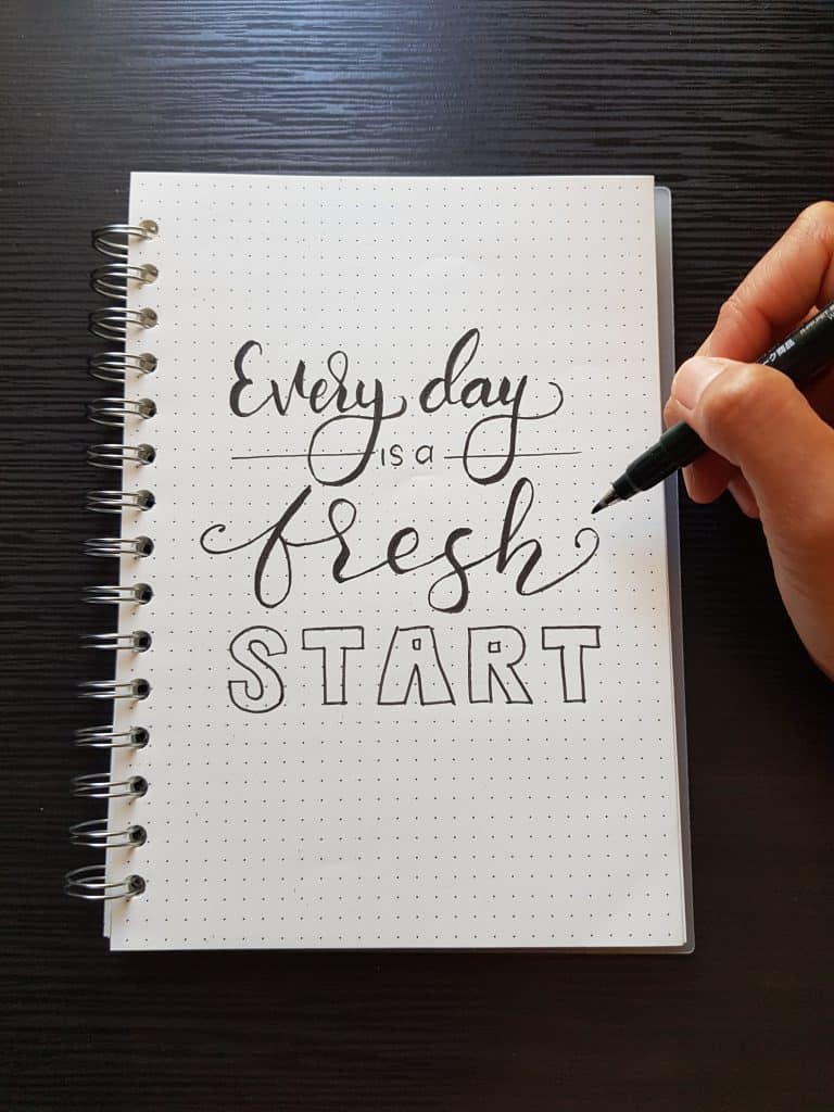 a photo of a notebook with a quote written that says "Every day is a fresh starts"