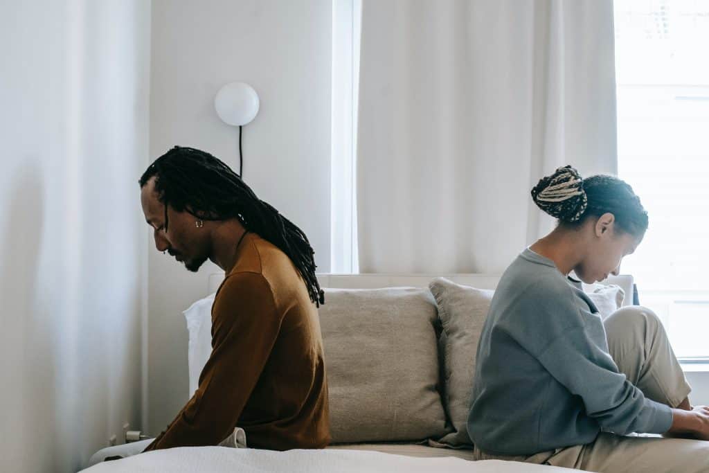 black couple sitting on the couch turning their back to each other