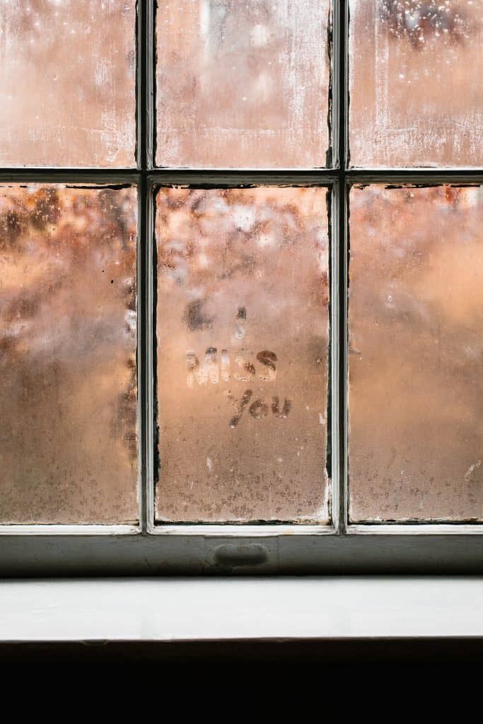 a glass window with fog that has the words "I miss you" written on it
