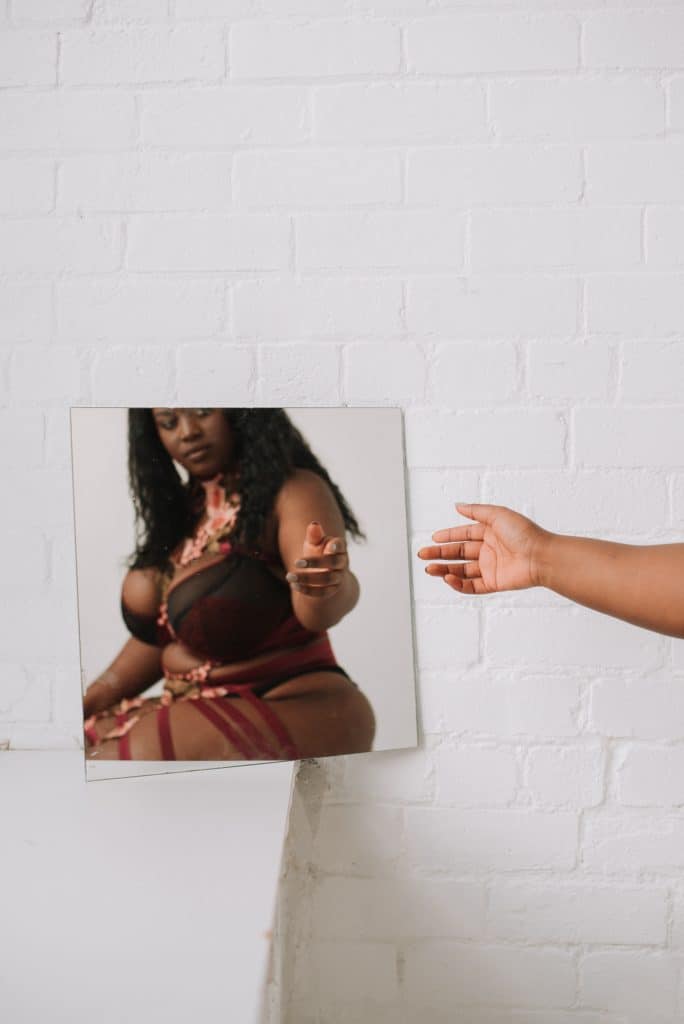 a black woman looking a herself in the mirror